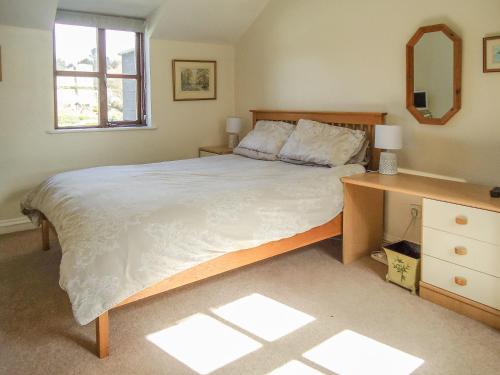 a bedroom with a large bed and a desk at Florin Cottage in Lerryn