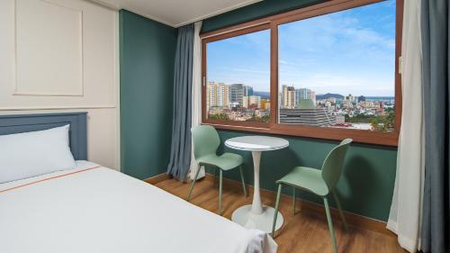 una camera con letto e finestra, tavolo e sedie di Hiker Hotel a Jeju