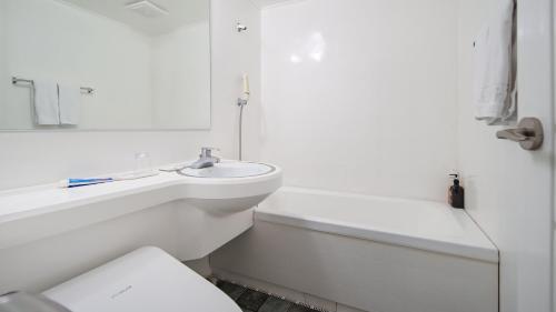 bagno bianco con lavandino, vasca e servizi igienici di Hiker Hotel a Jeju