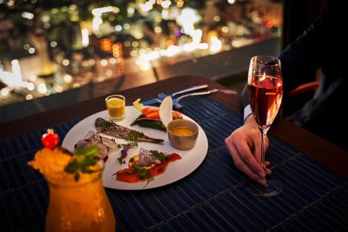 a table with a plate of food and a glass of wine at Centara Grand Hotel Osaka in Osaka
