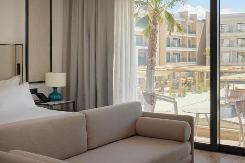 a hotel room with a couch and a bed and a balcony at Meliá Durrës Albania in Durrës