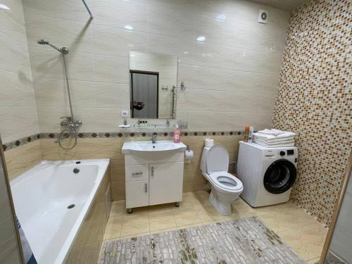 a bathroom with a tub sink and a washing machine at Comfortable apartments complex at Nova Garden near Disney Land in Tashkent
