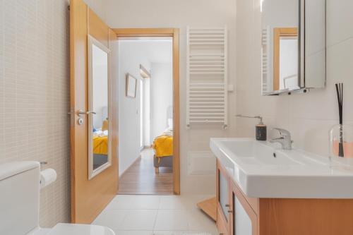 ein weißes Badezimmer mit einem Waschbecken und einem Spiegel in der Unterkunft Apartamento Figueiras in Nazaré