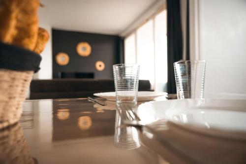 a table with two glasses and plates on it at Le Rose - Centre Ville - Wifi in Dunkerque