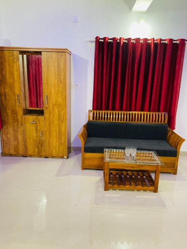 uma sala de estar com um sofá e uma cortina vermelha em Flowers Villa em Ambalavayal