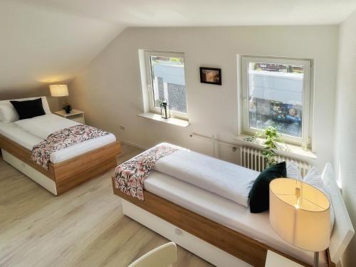 2 Betten in einem kleinen Zimmer mit 2 Fenstern in der Unterkunft Pension Zur Mühle in Grifte