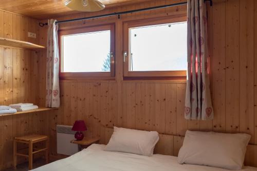 une chambre avec un lit et deux fenêtres dans l'établissement Chalet Le Lapye, aux Gets