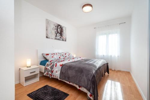 ein weißes Schlafzimmer mit einem Bett und einem Fenster in der Unterkunft Apartments Sandra in Turanj