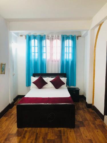 sypialnia z dużym łóżkiem z niebieskimi zasłonami w obiekcie Darjeeling Homestay w mieście Dardżyling