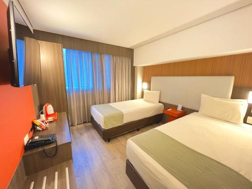 リオデジャネイロにあるeSuites Hotel Recreio Shoppingのベッド2台とテレビが備わるホテルルームです。