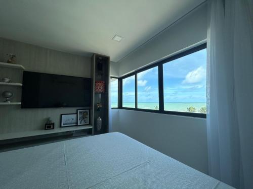 een slaapkamer met een bed en een groot raam bij Flat Suites Super Luxo in Maceió
