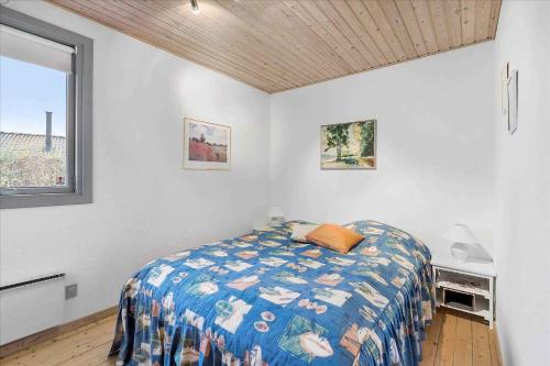 1 dormitorio con 1 cama con edredón azul y ventana en Lovely Holiday Home On The Beach At Trres, en Otterup