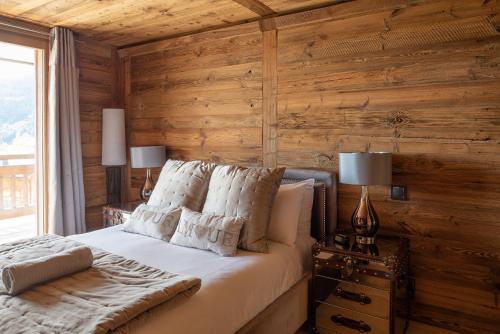 - une chambre avec des murs en bois et un lit avec des oreillers blancs dans l'établissement Chalet Louis, aux Gets