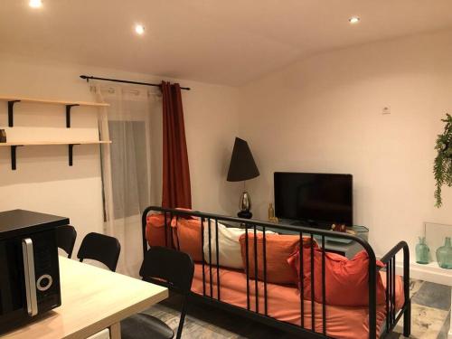 Zimmer mit einem Bett, einem TV und einem Sofa in der Unterkunft Charmant T2 climatisé - Près des plages in Narbonne