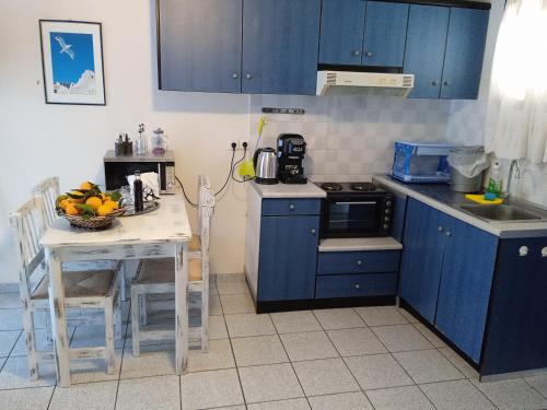 a kitchen with blue cabinets and a table with a bowl of fruit at Sea waves apartments in Nea Epidavros