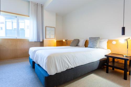 Un dormitorio con una cama grande y una ventana. en Oporto City View - Guest House Suites, en Oporto