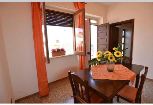 einen Esstisch mit einer Blumenvase darauf in der Unterkunft Casa Salento Maria in Marina di Mancaversa