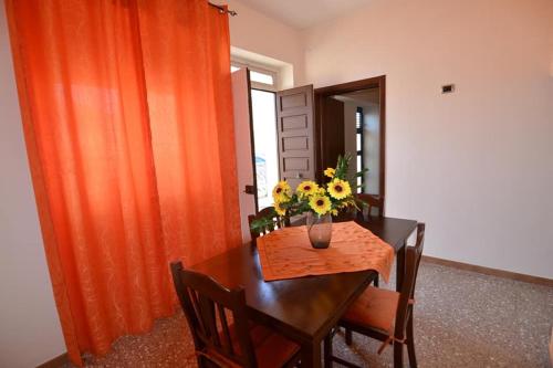 einen Esstisch mit einer Blumenvase darauf in der Unterkunft Casa Salento Maria in Marina di Mancaversa