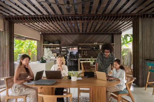 a group of people sitting at a table with laptops at Tanaga CoLiving in Seminyak