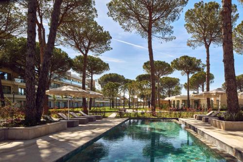 an image of a pool with trees and umbrellas at Meliá Durrës Albania in Durrës