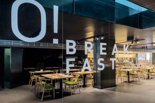 a restaurant with tables and chairs in front of a sign at Occidental Diagonal 414 in Barcelona