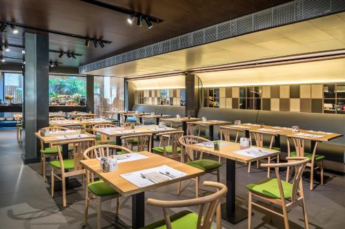 a restaurant with wooden tables and green chairs at Occidental Diagonal 414 in Barcelona