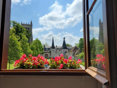 a window with flowers in front of a castle at La Porterie face à l'abbaye in Le Bec-Hellouin