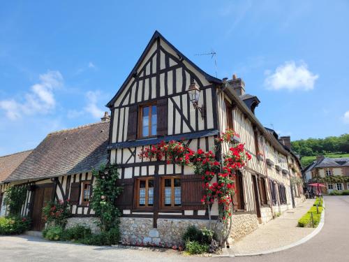 a black and white building with red flowers on it at La Porterie face à l'abbaye in Le Bec-Hellouin