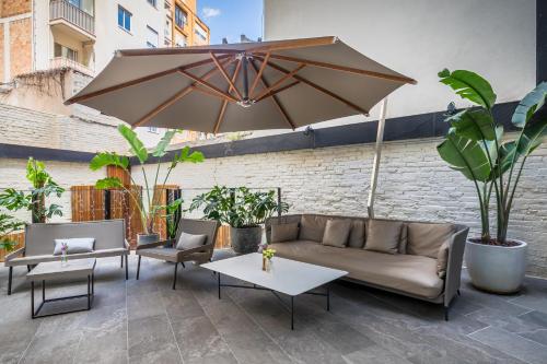 a patio with a couch and tables and an umbrella at Occidental Diagonal 414 in Barcelona