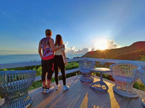 a couple standing on a deck looking at the sunset at A Promised Land BnB in Jiufen
