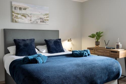 una camera da letto con un letto con coperte blu e cuscini di Exclusive House with Canadian Hot Tub a Great Yarmouth