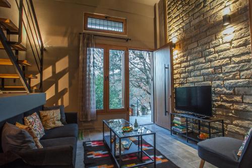 sala de estar con TV y pared de piedra. en Acorn's Houses, Gray and Green Acorn, 