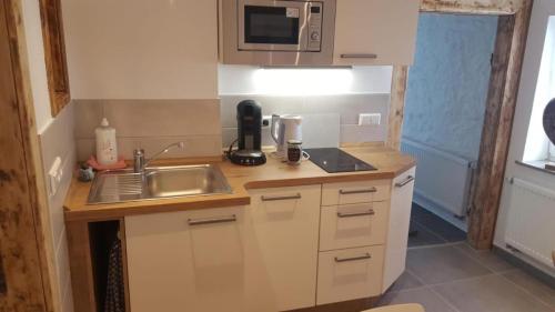 a small kitchen with a sink and a microwave at Cafe-Konditorei-Pension Sander in Niederfell