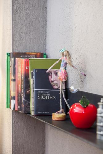 a barbie doll on a shelf with books and a tomato at Acorn's Houses, Gray and Green Acorn in Kalloní