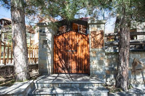 a wooden door in a stone wall with two trees at Acorn's Houses, Gray and Green Acorn in Kalloní
