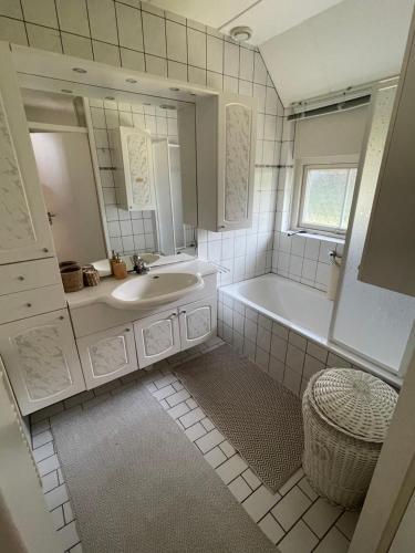 a white bathroom with a tub and a sink at Freistehendes Ferienhaus am See Nähe Roermond in Heel