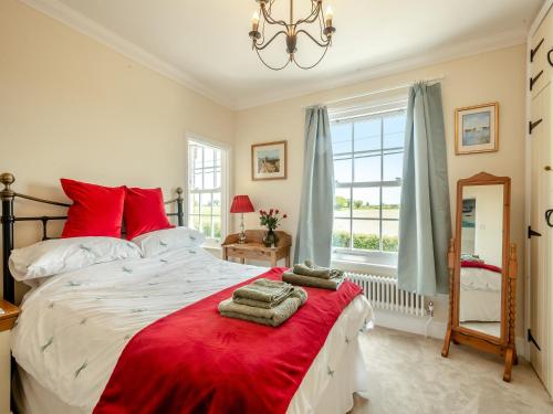 um quarto com uma cama grande e almofadas vermelhas em Bells Cottage em Wrentham