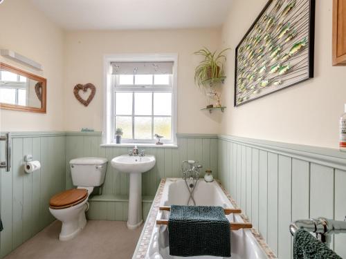 uma casa de banho com um WC, um lavatório e uma banheira em Bells Cottage em Wrentham