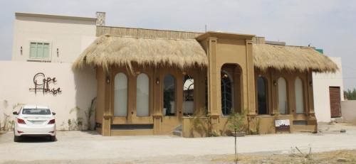 a building with a straw roof and a white car parked outside at Cape House in Amritsar