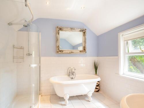 La salle de bains est pourvue d'une baignoire blanche et d'un miroir. dans l'établissement Cartref, à Capel-Curig