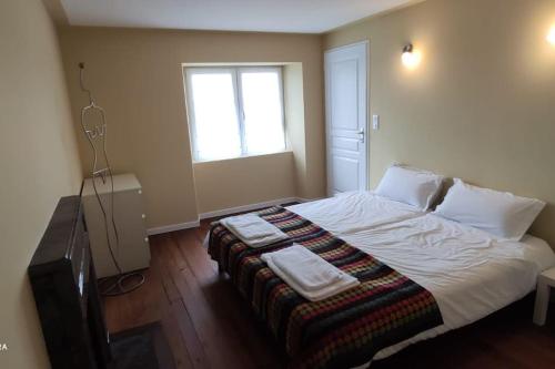 - une chambre dotée d'un grand lit avec des draps blancs et une fenêtre dans l'établissement maison de charme avec jardin, à Cousance