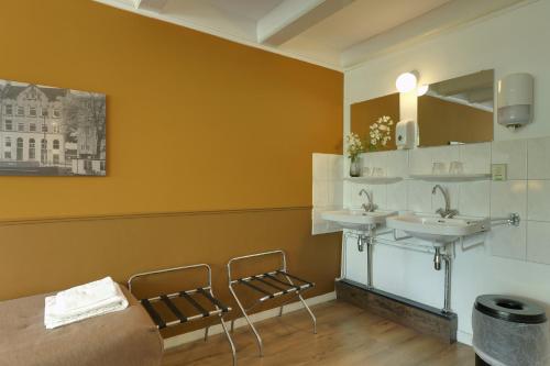 een badkamer met 2 wastafels en 2 stoelen bij Hotel Prinsenhof Amsterdam in Amsterdam