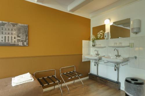 a bathroom with two sinks and two chairs at Hotel Prinsenhof Amsterdam in Amsterdam