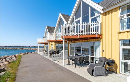 a yellow house with a deck and chairs and the water at Beach Front Home In Hasle in Hasle