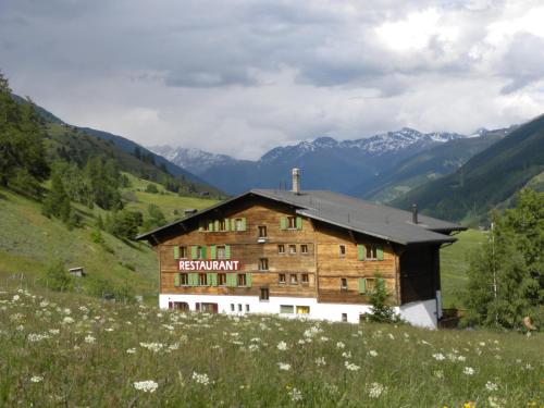 a building on a hill with mountains in the background at Hotel Restaurant Walliser Sonne in Reckingen - Gluringen