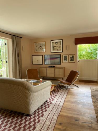 ein Wohnzimmer mit einem Sofa, Stühlen und einem TV in der Unterkunft Peaceful cottage with private garden in Hailsham