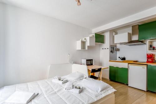 Cet appartement comprend une chambre avec un lit et une cuisine avec des placards verts. dans l'établissement Studio Zielon - Welkeys, à Avignon