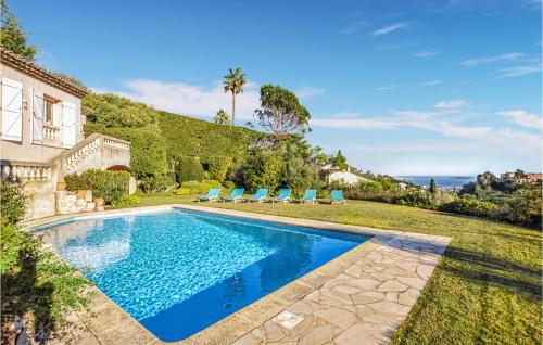 una piscina nel cortile di una casa con sedie a sdraio blu di 5 Bedroom Gorgeous Home In Mandelieu-la-napoule a Mandelieu La Napoule