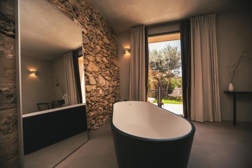 a bathroom with a white tub and a stone wall at Rakalia Pure Living Sicilian Retreat in Marsala