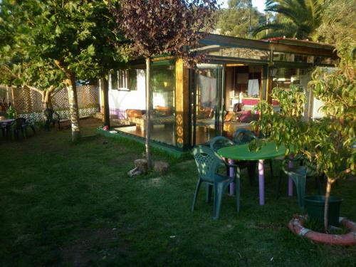 a house with a table and chairs in a yard at Cabaña rustica en plena naturaleza en playa de Nerga, Ría de Vigo, in Hio